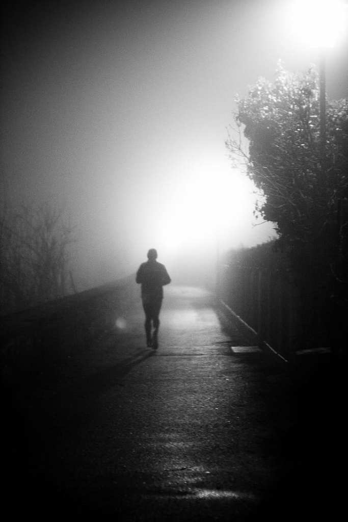 Black and white photograph of a man jogging on a road